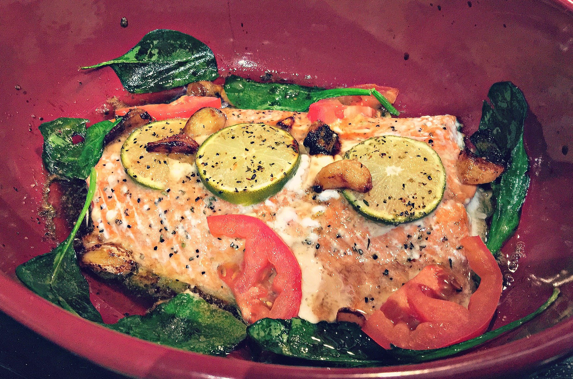 Baked Salmon With Spinach, tomatoes, candied garlic cloves, green onion and a honey lime sauce. 