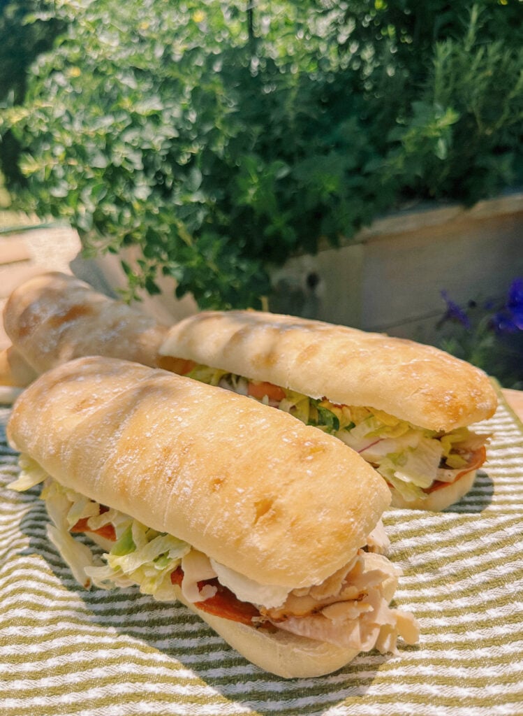 Italian subs, Italian sub recipe, homemade Italian subs, pool day sandwiches, summer sandwich recipes, easy Italian sandwich, toasted Italian subs, deli style subs, Italian hoagie recipe, summer lunch ideas, crowd pleasing sandwiches, family lunch recipes, sandwich recipes for a crowd, mozzarella Italian sandwich, pesto Italian subs, homemade Italian dressing, picnic sandwich ideas, beach sandwiches, pool party food ideas, easy summer meals, Italian grinder sandwich, grinder sandwich recipe, layered Italian sandwich, cold sandwich recipes, hot Italian sandwich, salami sandwich recipe, turkey and salami sandwich, fresh mozzarella sandwich, banana pepper sandwich, bakery bread sandwiches, easy entertaining recipes, lunch sandwich ideas, make ahead sandwiches, summer entertaining food, Italian deli sandwich, crispy lettuce sandwich, oven baked subs, easy pool day food, family friendly sandwiches
